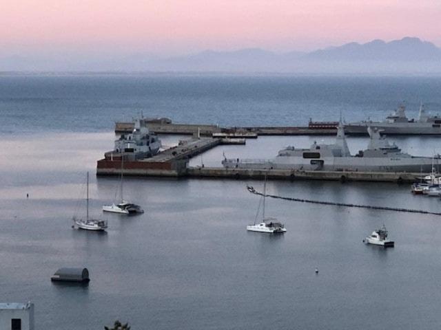 a group of boats in a harbor with a large ship at Essio's Garden Apartment, Simons Town South Africa in Simonʼs Town