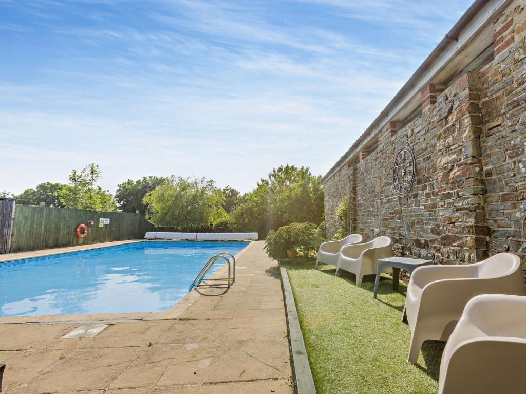 Una piscina con sillas al lado de un edificio de ladrillo. en 4 Bed in Westward Ho 46838, en Westward Ho