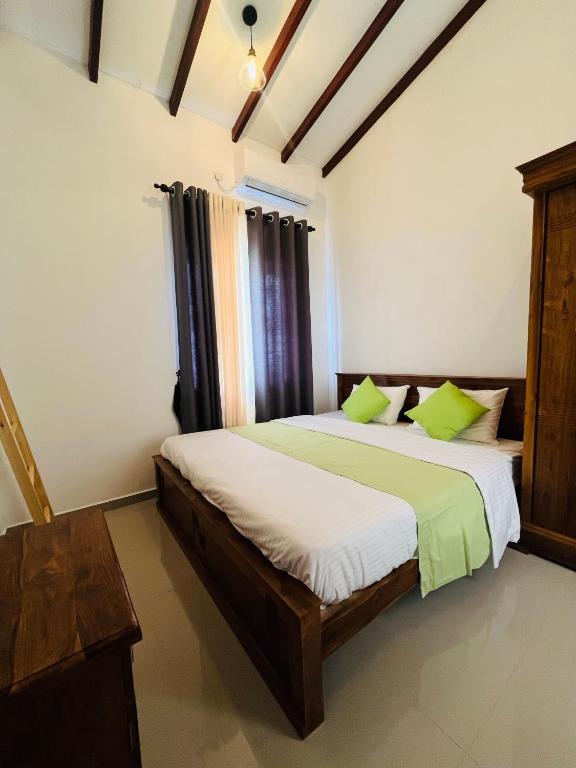 a bedroom with a bed with white sheets and green pillows at Celestial Negombo Resort Transit Stopover Villa 85 in Negombo