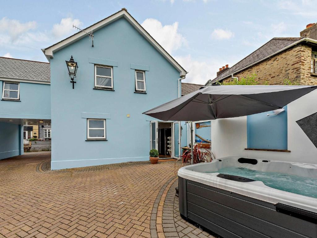 a blue house with a hot tub and an umbrella at 4 Bed in Combe Martin 83502 in Combe Martin