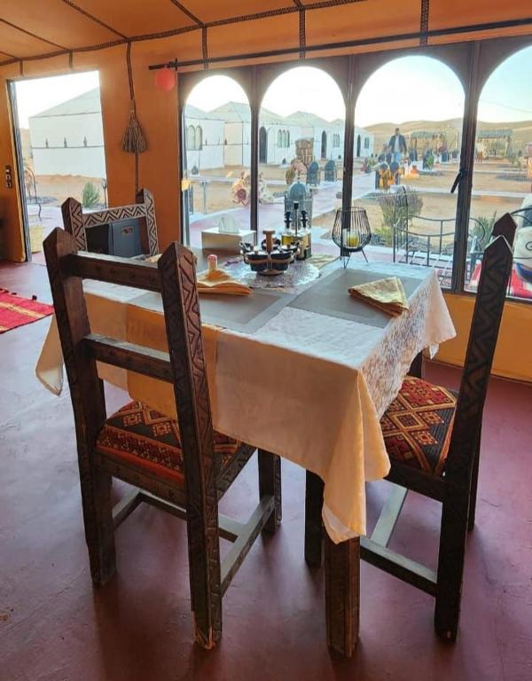 a dining room table and chairs with a view of the desert at Original Luxury Camp in Merzouga