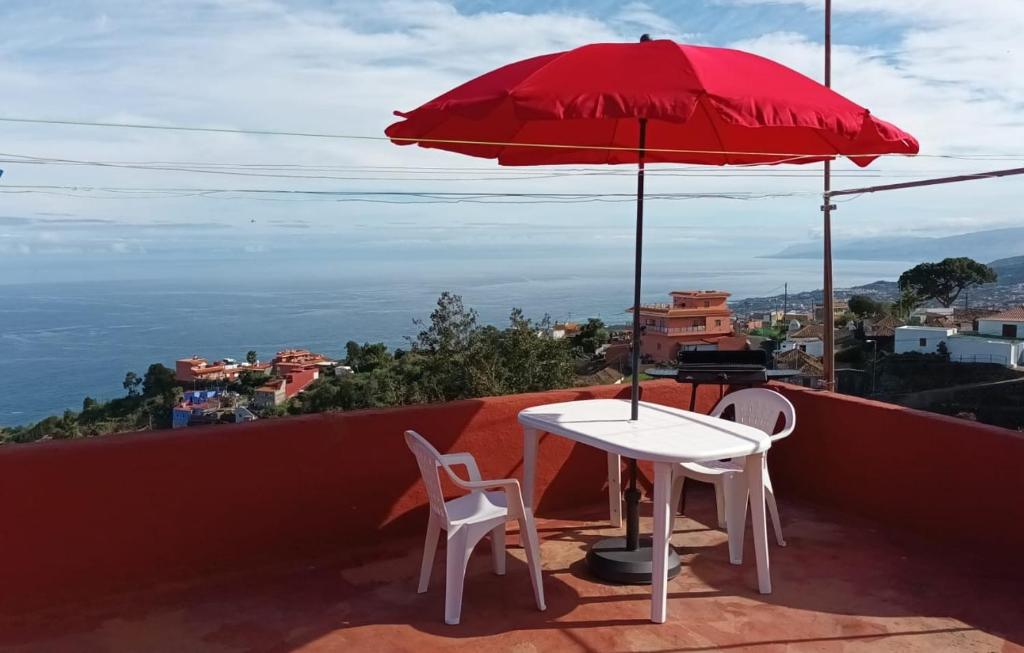 a red umbrella and a table and chairs on a roof at Ferienwohnung echt kanarisch mit Meer und Teide Blick La Vega Teneriffa Nord in Icod de los Vinos