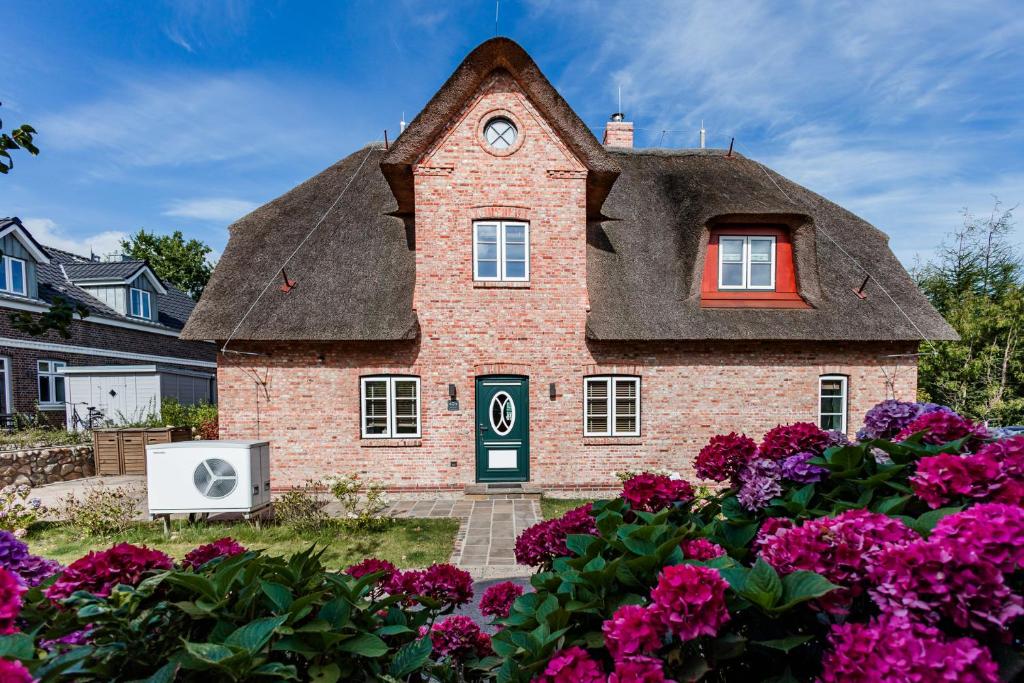 a house with a clock on the roof with flowers at Lokelk Lunhüs Hausteil 3 in Oevenum