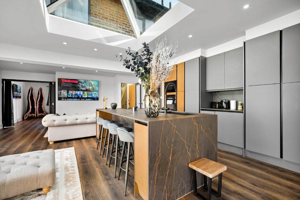 a kitchen with a bar with stools and a couch at Superb Luxury 3 Bedroom House - Garden - Parking - Outdoor Playground 17P in Birmingham