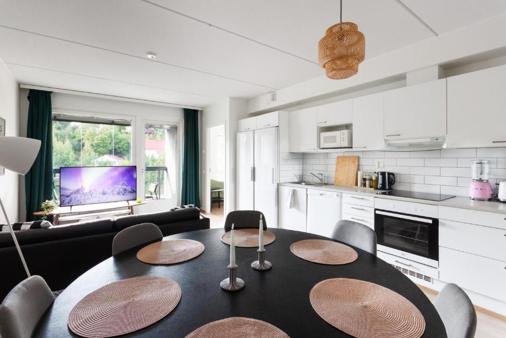 a kitchen and living room with a table and chairs at Cosy family apartment with parking, sauna and balcony in Jyväskylä
