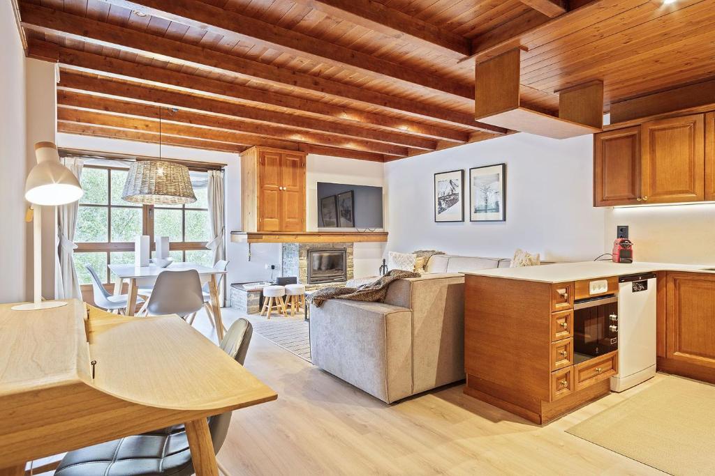 a kitchen and living room with wooden ceilings at Luderna - Apartamento Val de Ruda A5 Orla in Baqueira-Beret