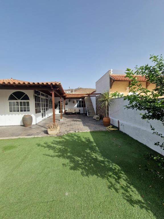 Una casa con un césped verde delante de ella. en Villa Palmera Dorada, en Mogán