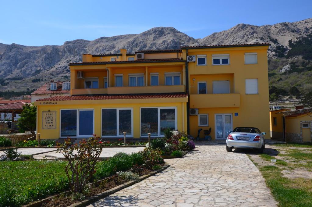 a yellow house with a car parked in front of it at Bed & Breakfast Dani in Baška