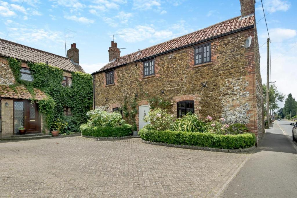 ein altes Backsteingebäude in einer Kopfsteinpflasterstraße in der Unterkunft Carrstone Cottage in Grimston