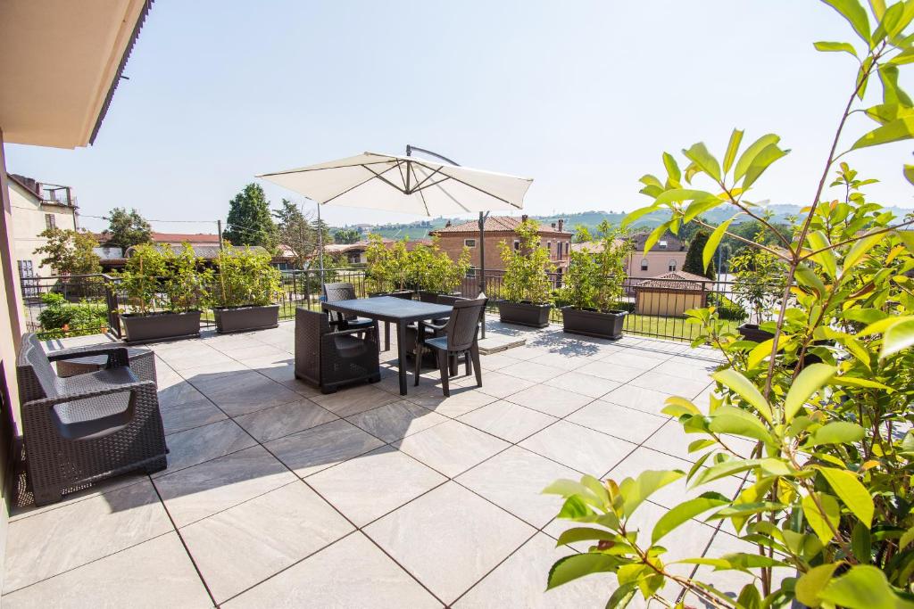 a patio with a table and chairs and an umbrella at Casa Baratta - La terrazza sulle Langhe in Neive