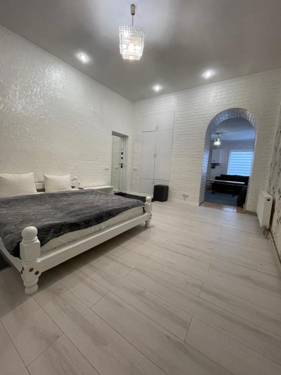 ヴィーンヌィツャにあるCenter apartmentのベッドとシャンデリアのある白い寝室