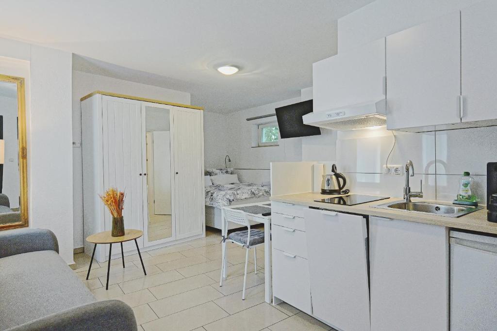 a kitchen with white cabinets and a living room at Smart-Apartment in Bamberg in Bamberg