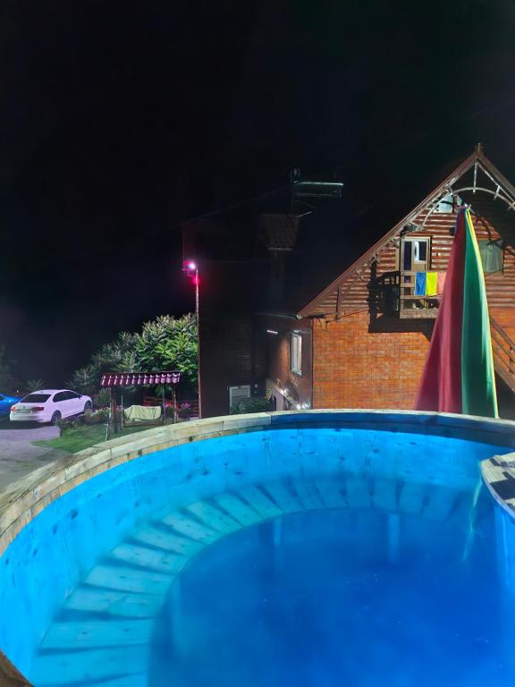 a swimming pool in front of a house at night at Pensiunea Cabana Viselor ,Apuseni in Vadu Moţilor