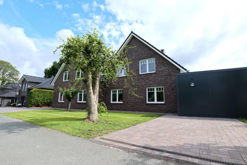 a brick house with a tree in the driveway at Ferienwohnung Linus OG 95172 in Rhauderfehn