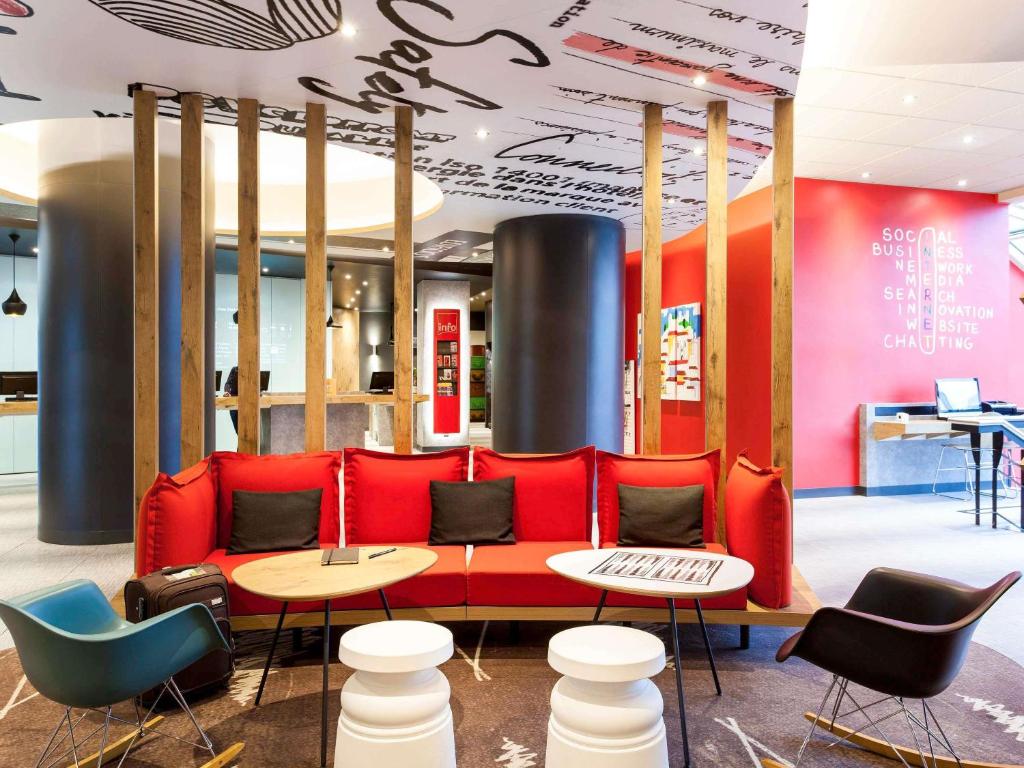A colorful lobby lounge with a red sofa, armchairs, and small tables.