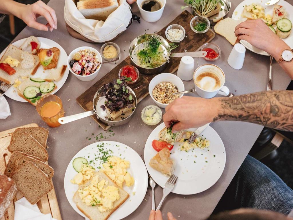 A busy breakfast table with breads, spreads, fruit, eggs, and coffee.