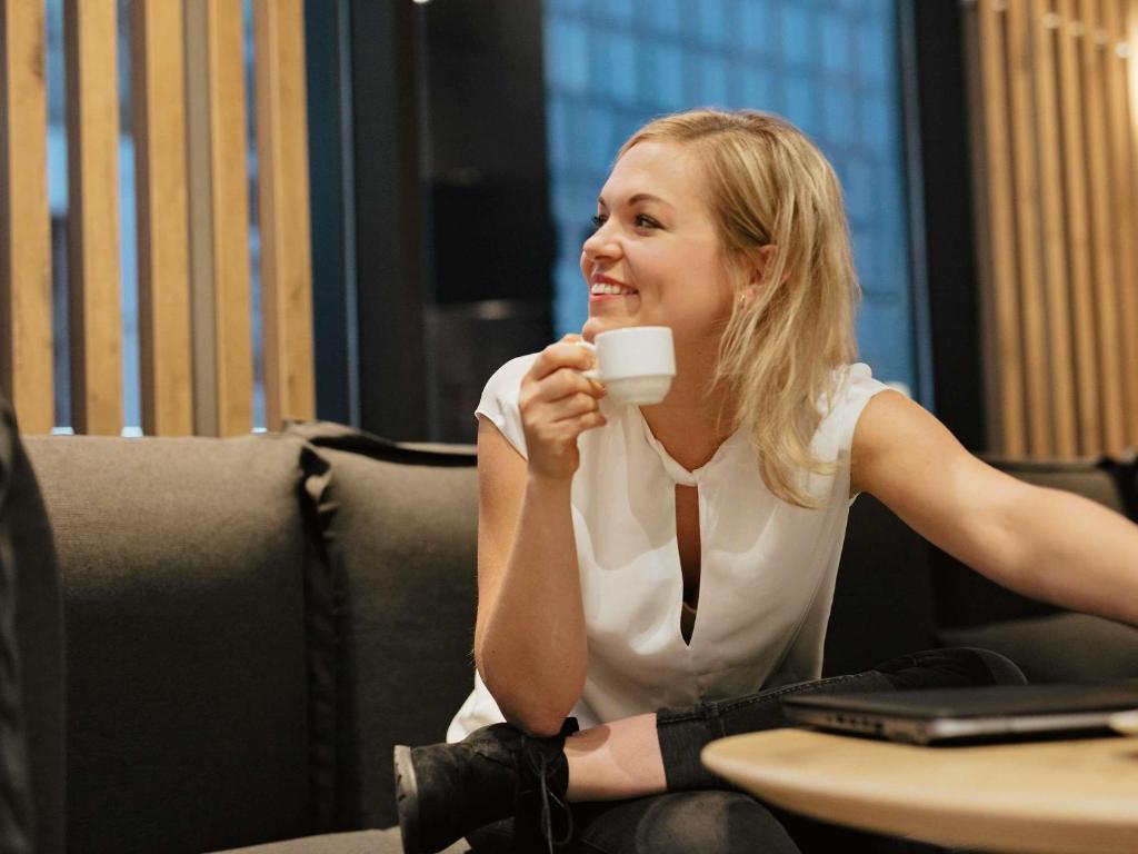 A guest drinking coffee at a lobby lounge table beside a laptop.