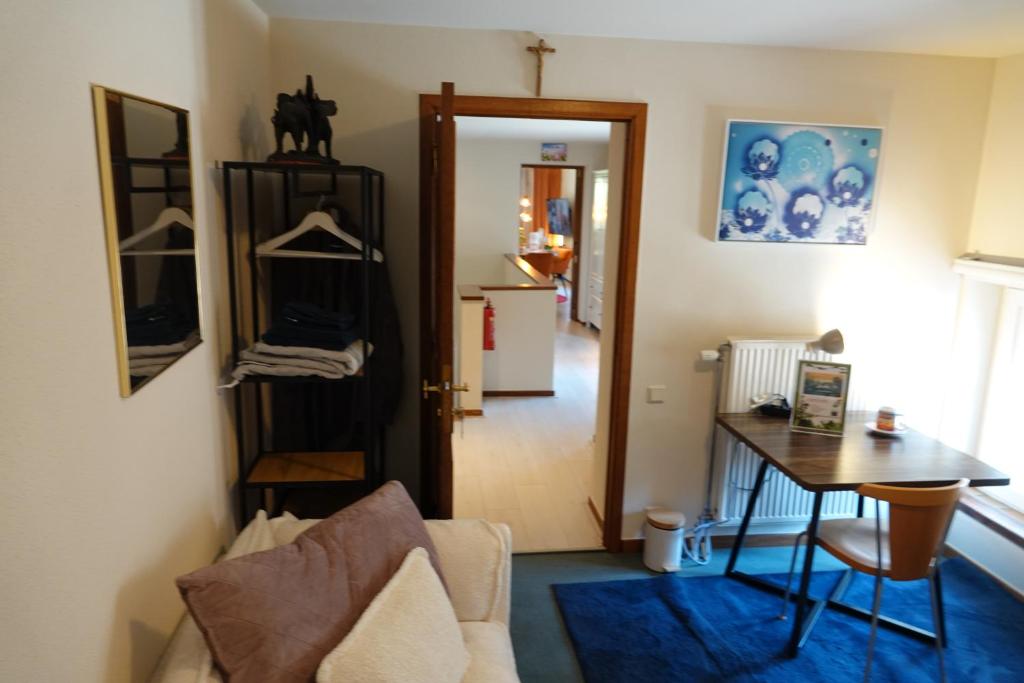 a living room with a desk and a table and a door at Le Grand Jardin in Dalhem