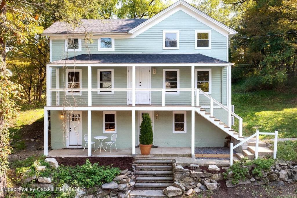 a white house with a porch and a table at Huge Modern Chalet on Trestle Trail New Paltz & Rosendale in Rosendale