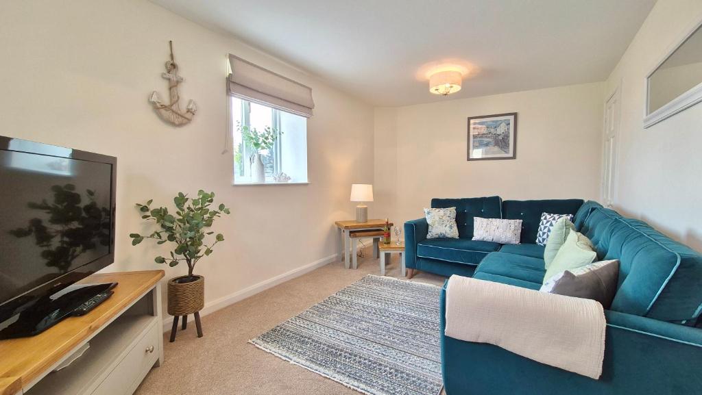 a living room with a blue couch and a tv at Seabreeze Cottage 2 bedroom - Sleeps 6 - Bron-Y-Wendon Holiday Park in Llanddulas