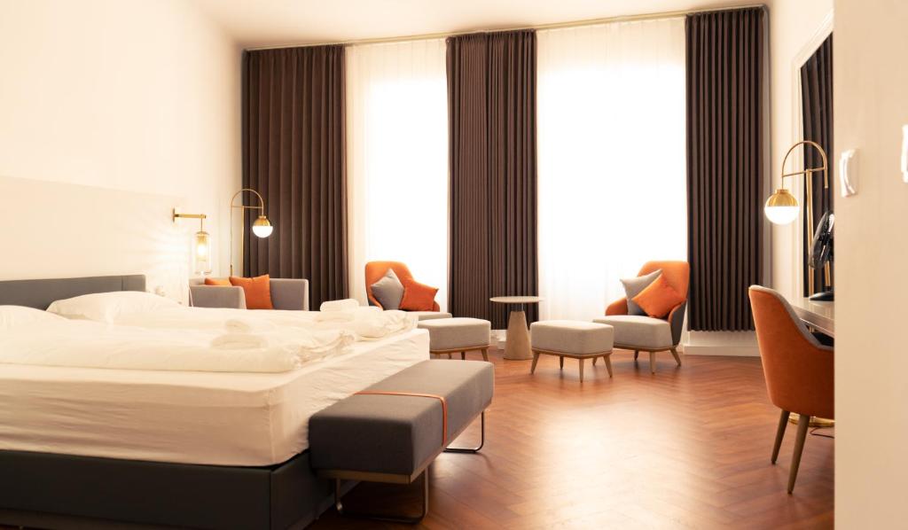 a hotel room with a large bed and chairs at Elias Residence Vienna in Vienna