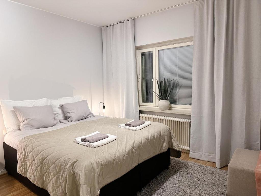 a white bedroom with a bed with towels on it at Bright & Cozy 1BR Home in Central Lahti in Lahti