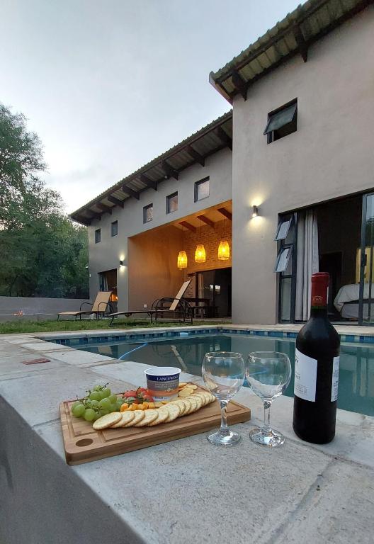 a bottle of wine and glasses on a table near a pool at Afri Villa Stays - Luxury Bush Villa Hyena in Marloth Park