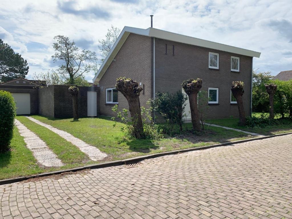 a house with trees in front of a brick driveway at de Brabander in Cadzand