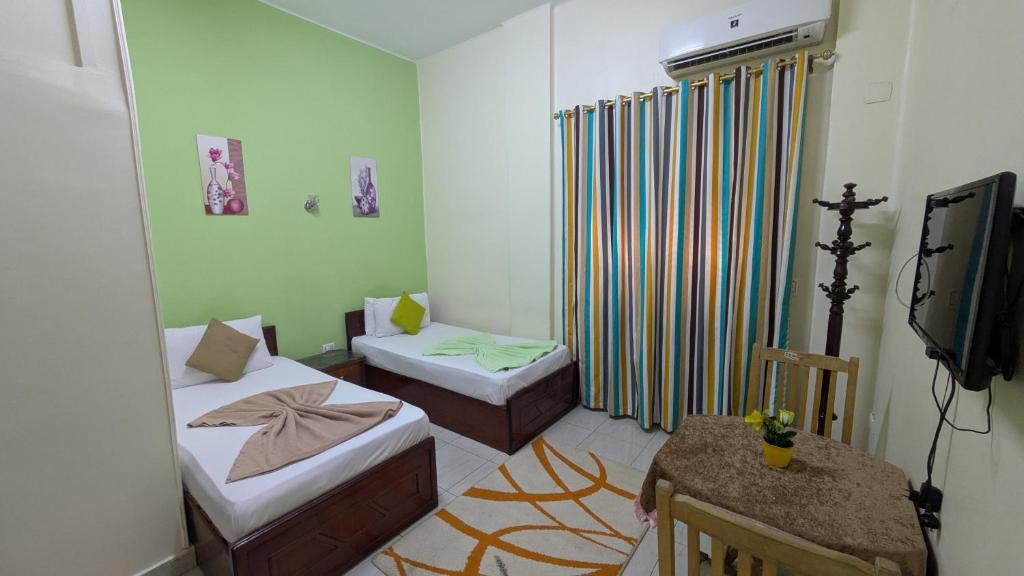 een kleine kamer met 2 bedden en een televisie bij Golden Star Hostel in Caïro