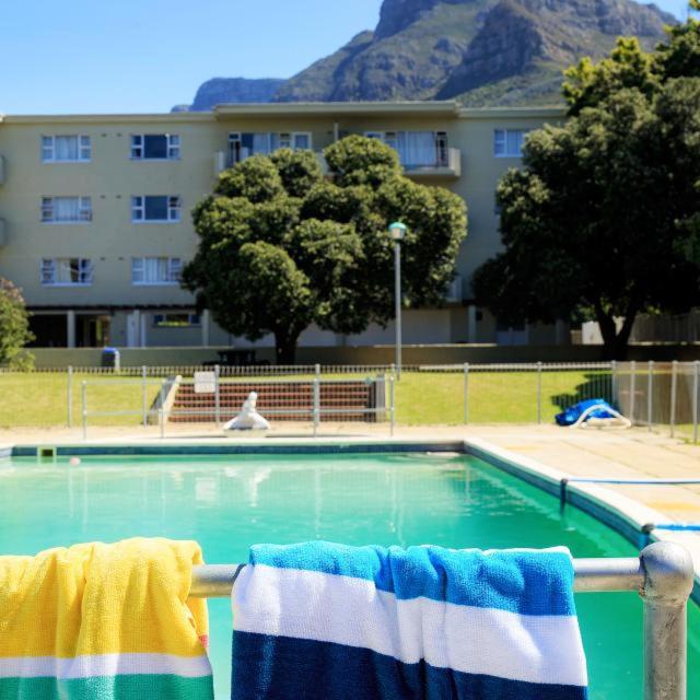 a swimming pool with two towels hanging on a rail at Forest Hill Backpackers in Cape Town