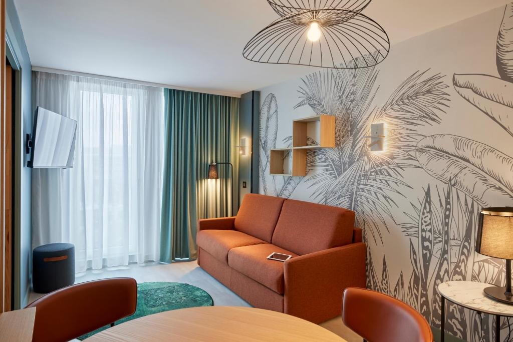 a hotel room with a couch and a table at Aparthotel Adagio London City East in London