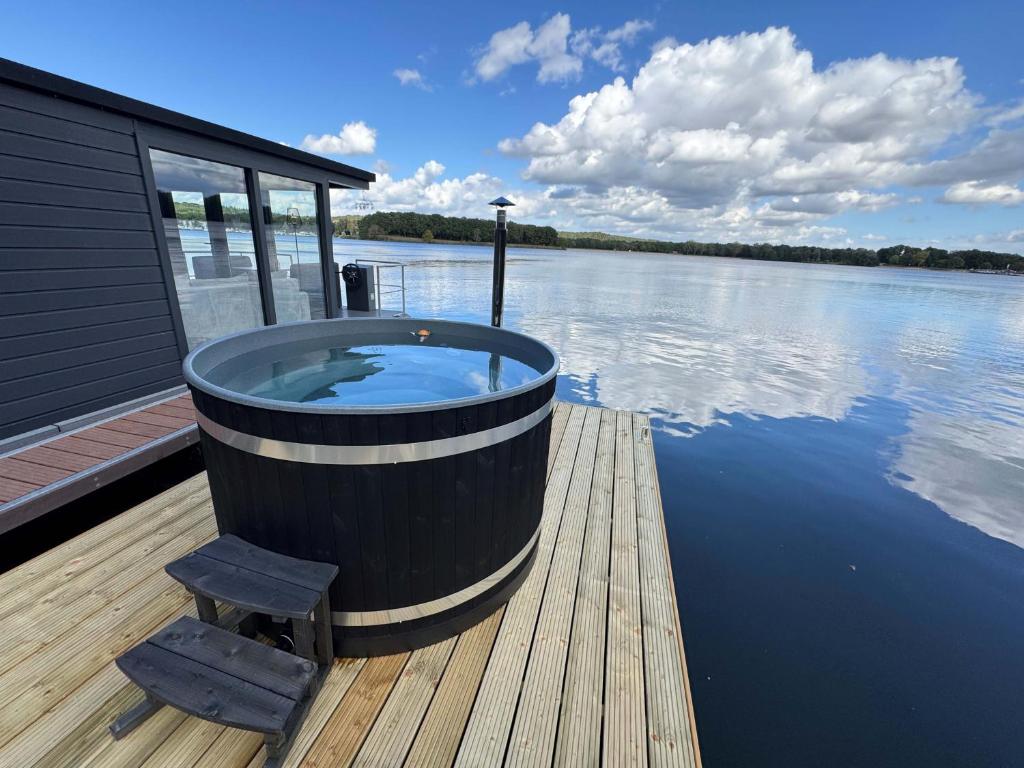 a large tub sitting on a dock on a body of water at Houseboat Mookerplas met Hottub in Middelaar