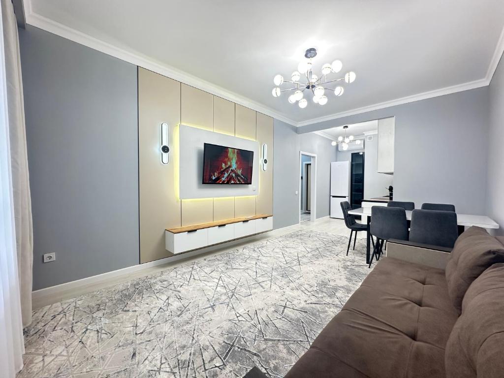 a living room with a couch and a dining room at Двухкомнатная квартира с евроремонтом в центре Алматы, рядом с ТРЦ MEGA Center in Almaty