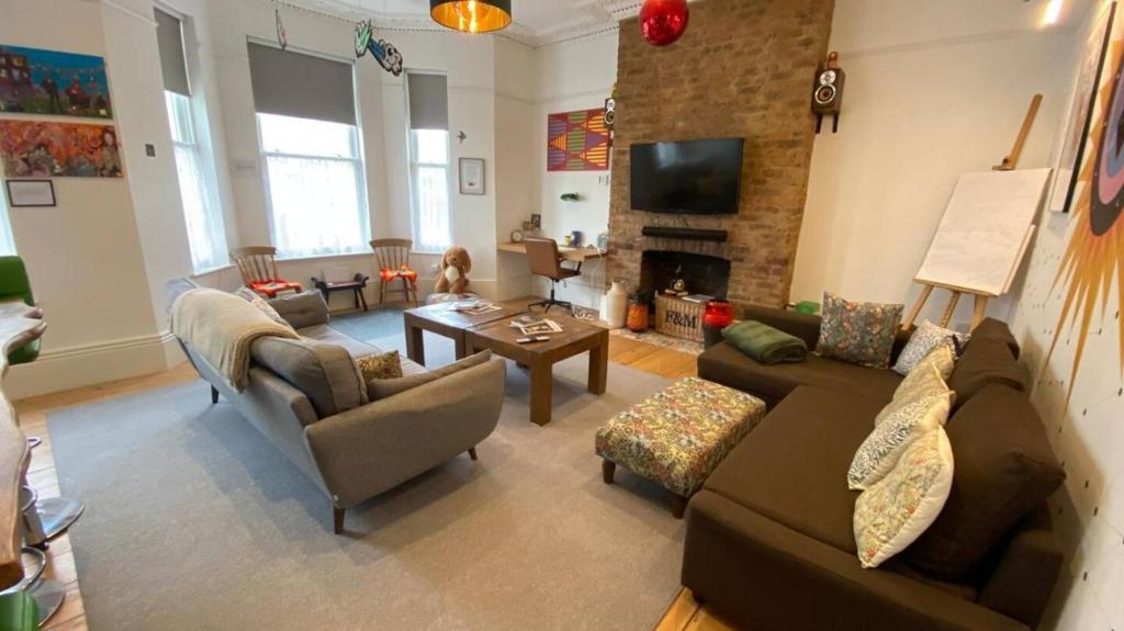 a living room with a couch and chairs and a fireplace at Coastal Victorian Apartment W Charm in Hastings