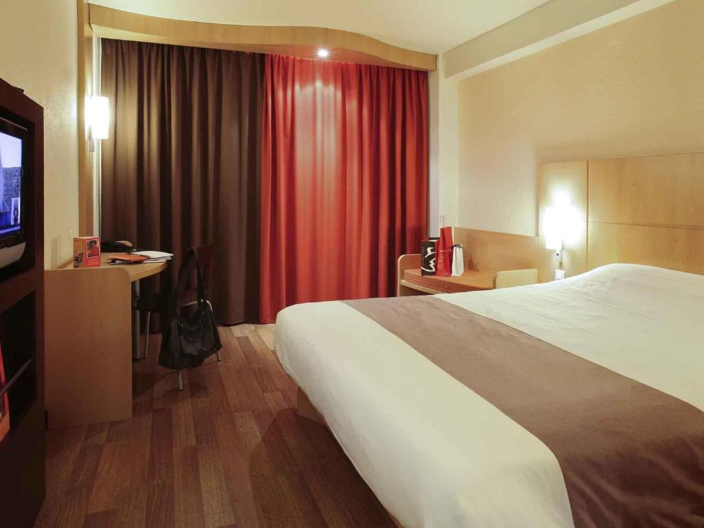 ブラガにあるHotel ibis Bragaの大きなベッドとテレビがあるホテルの部屋