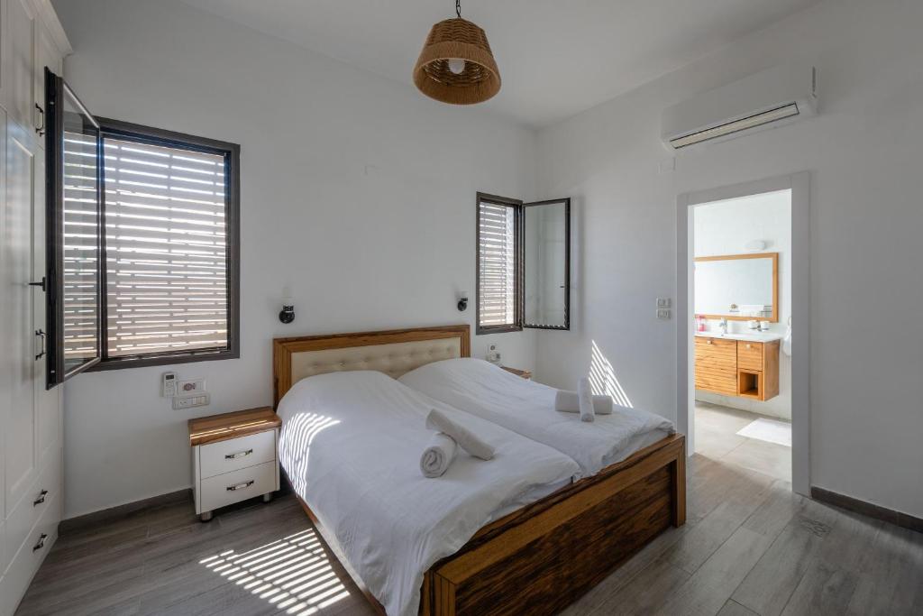 a bedroom with a large bed with white sheets at The Stone Villa Luxury Nature Retreat Galilee in Hosha‘ya
