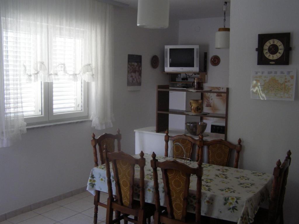 uma sala de jantar com mesa e cadeiras e uma televisão em Apartments Roviš em Tar