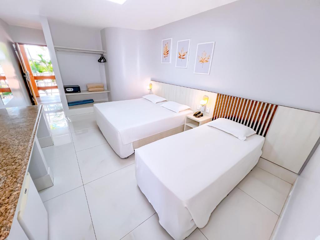 due letti in una stanza con pareti bianche di Hotel Roma direto com o Grupo diRoma com acesso ao Acqua Park e Café da manhã a Caldas Novas