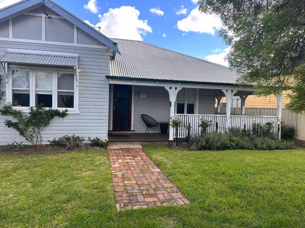 a house with a chair on the front yard at Wattle Cottage in Cootamundra