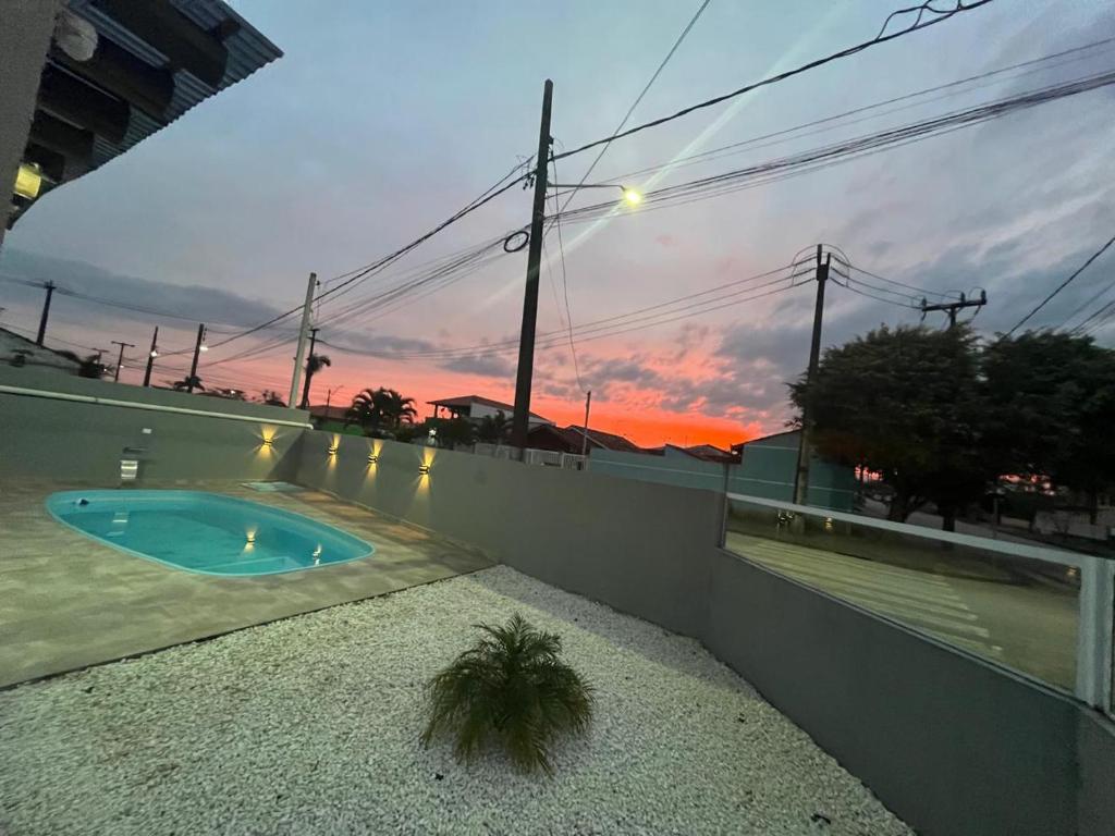Una piscina con una puesta de sol al fondo en Residencial Day off, en Guaratuba