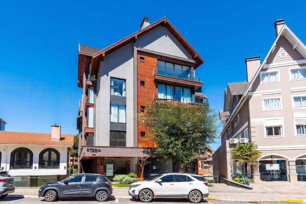 ein Gebäude mit einem Dach auf einer Straße mit geparkten Autos in der Unterkunft Rosa Edificio Residencial Storia in Gramado