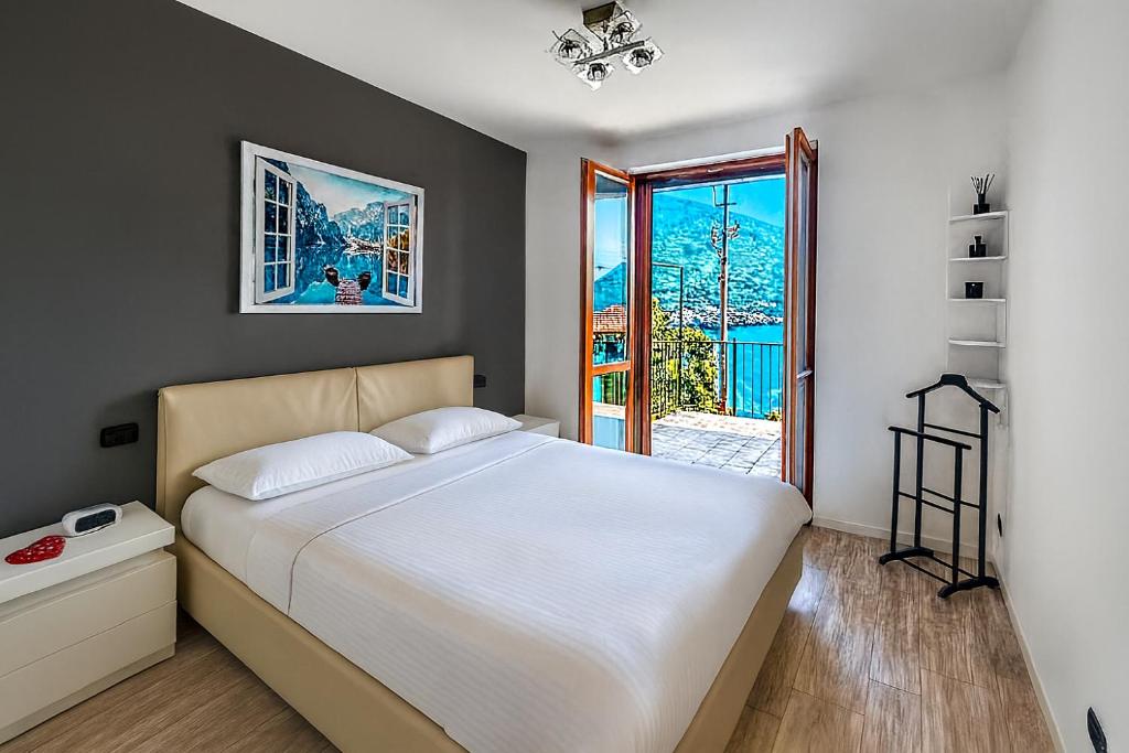 a bedroom with a large white bed and a window at Casa A&E - Panoramic Lake Orta Views in Oira