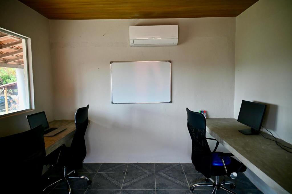 a room with a desk with two monitors and chairs at Suite Lua - Quarto e Banheiro com Ar Condicionado no Macapa Paradise in Luis Correia