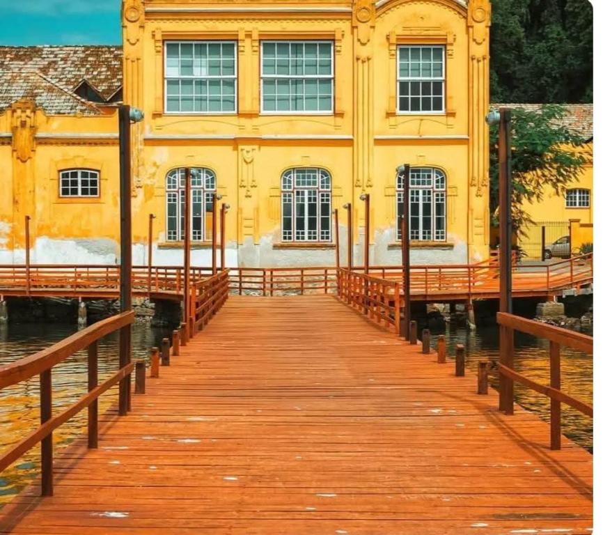 un molo di legno di fronte a un edificio giallo di CASA Vida a São Francisco do Sul