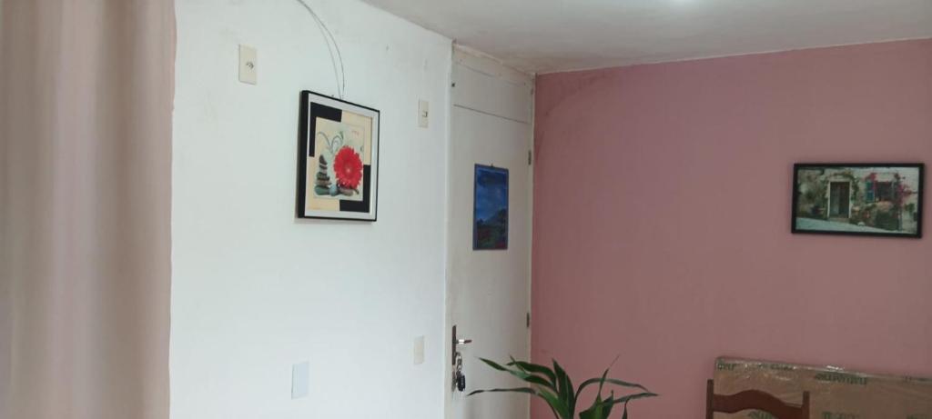a room with three pictures on a pink wall at Aconchego in Marituba