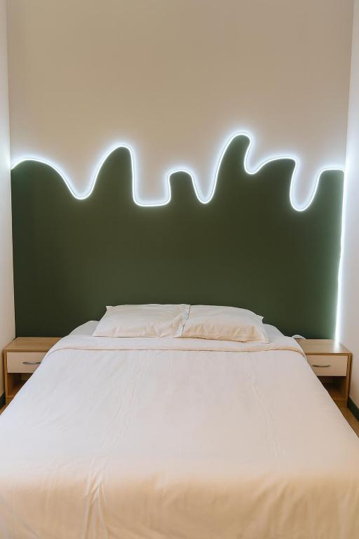 a bedroom with a large white bed with a green headboard at Chambre privée "verte" - Maison partagée in Amiens
