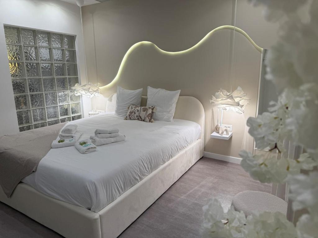 Un dormitorio blanco con una cama blanca y una ventana. en Spa sauna et hammam - Dahlia, en Belfort