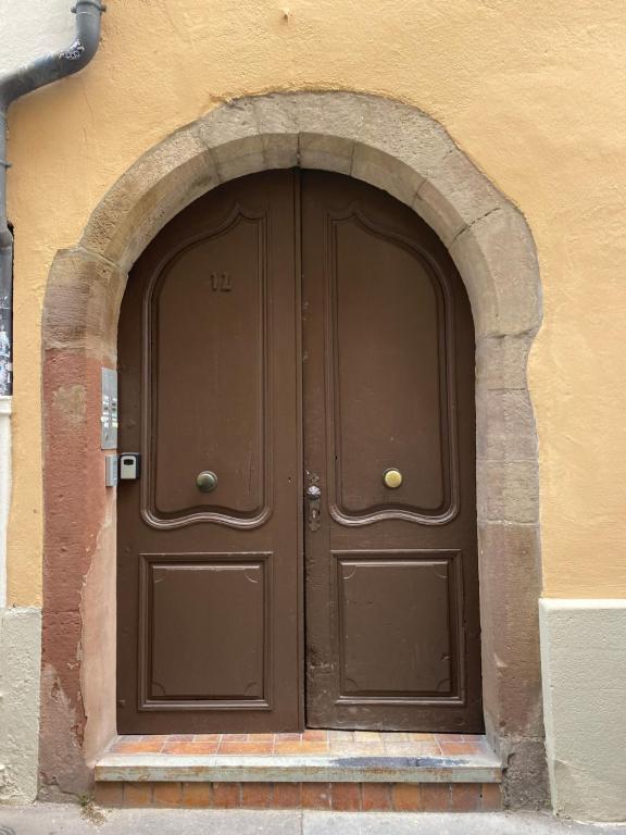 a large brown door with an arch in a building at Les appartements Hyper centre in Strasbourg