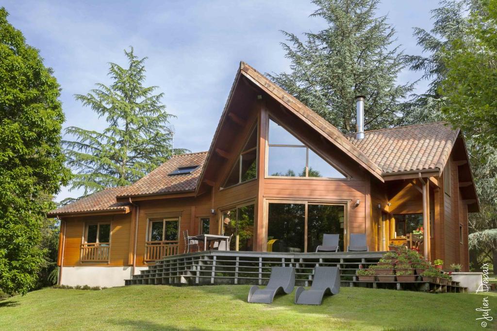 Cette maison en rondins dispose d'une grande terrasse et de fenêtres. dans l'établissement Chambres d'Hôtes Le Chalet, à Condat-sur-Vienne