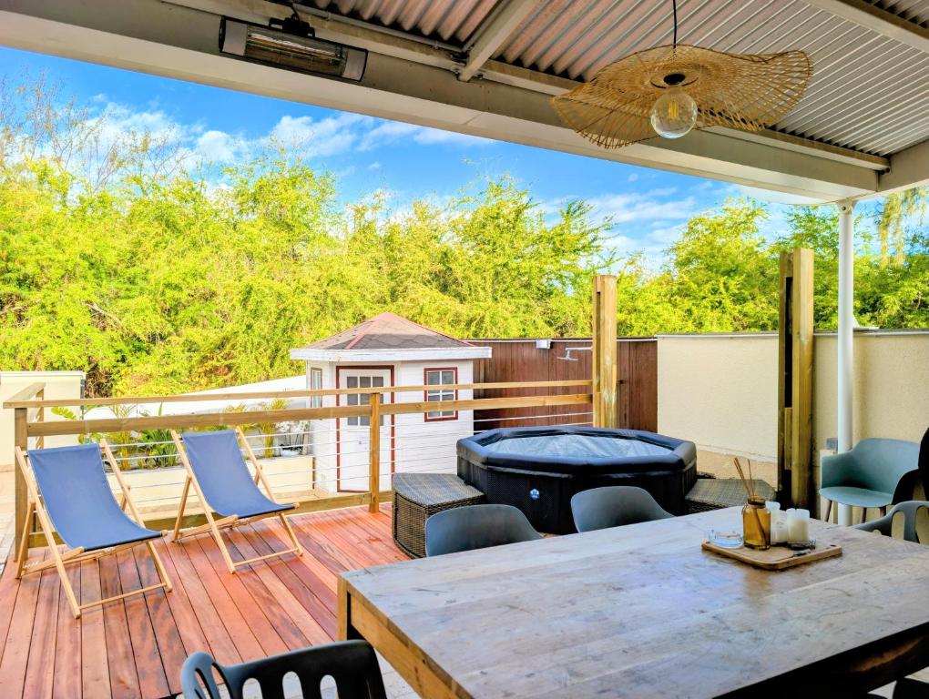 a patio with a table and chairs on a deck at Horizon plage - 3 chambres et spa in Saint-Paul